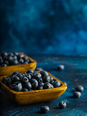 Blueberries in bowls on a dark blue background. Vitamins, antioxidants. Cooking, fillings for pies, juices, fresh juices. The medicine. Agriculture and forestry. Close-up.