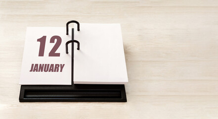 january 12. 12th day of month, calendar date. Stand for desktop calendar on beige wooden background. Concept of day of year, time planner, winter month
