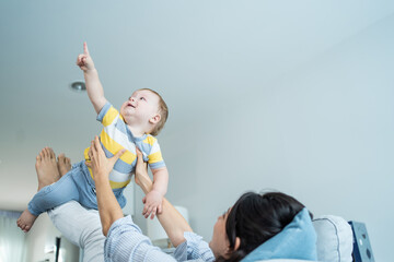 Caucasian loving mom play with baby boy child on sofa in living room. 