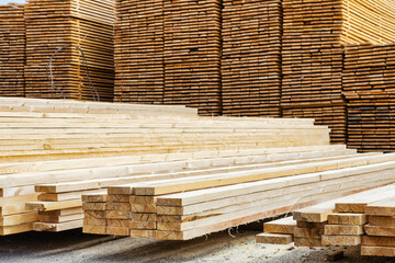 A lot of boards stacked on top of each other in a lumber yard. Wooden boards in the foreground close-up.