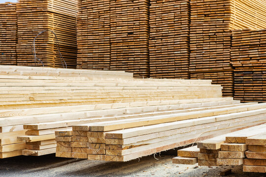 A lot of boards stacked on top of each other in a lumber yard. Wooden boards in the foreground close-up.