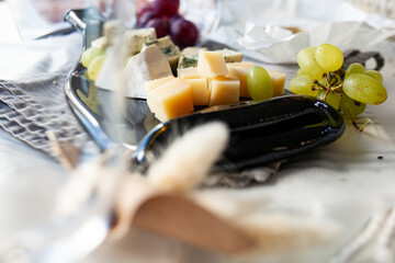 Cheese platter with different cheese and grapes, served on a glass transparent dish from a melted bottle