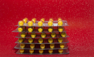 yellow capsules tablets in a silver blister on a red background