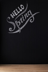 Hello spring. Seasonal photo, an inscription on a dark background of a slate wall or chalkboard....