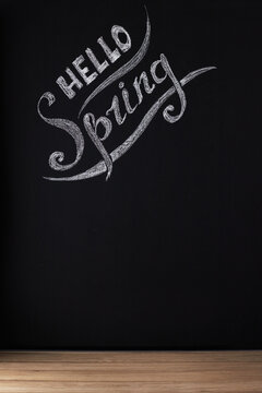 Hello spring. Seasonal photo, an inscription on a dark background of a slate wall or chalkboard. Front view. Place for text, copy space, mockup.