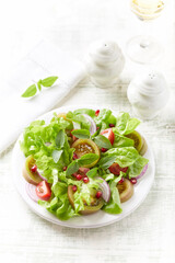 Salad with Tomatoes and Pomegranate Seeds on bright wooden Background. Copy space. 