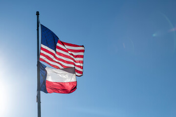 Sun Rays Lighting American Flag and Texas Flag Below on Flag Pole Blue Sky