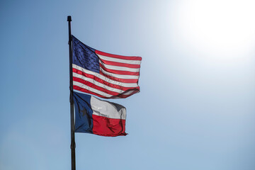 Bright Sun Rays Shining US American and Texas Flags on Pole Outside