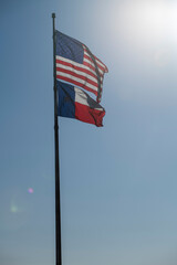 Bright Sun Rays and American USA Flag with Texas Flag Waving in Wind