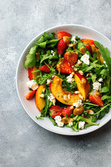 salad bowl with arugula, strawberry, cottage cheese, nectarine and peanut paste. healthy eating concept