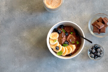 chocolate oatmeal porridge with blueberry, mint leaves and banana in a bowl. breakfast Concept