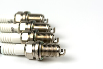 New spark plug on a white background, isolated. Group of four spark plugs for an automobile motor close-up. copy space