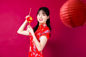 Beautiful Asian girl in traditional cheongsam on red background holding a lantern. Translation-...