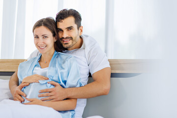 Obraz premium Lovely pregnant wife tenderly touch beloved belly of unborn baby while lounging on bed with smile and happy as enjoy watching entertainment media on computer