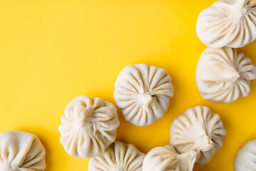 Traditional Georgian raw frozen khinkali on a yellow background flatlay