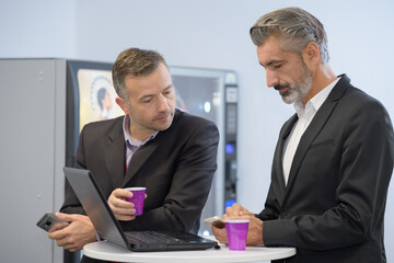 businessmen meeting up in a vending machine coffee pause