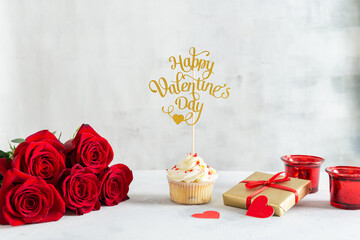 Cupcake with vanilla cream and red sugar hearts for St. Valentine's Day and roses bouquet with a gift on light background. Recipe, Romantic gift. Bakery, confectionery menu, greeting card Copy space