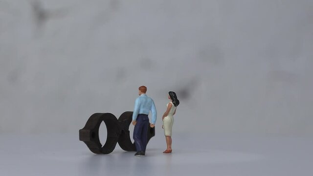 Concept about social prejudice. A miniature&nbsp;man and a miniature woman&nbsp;standing&nbsp;behind&nbsp;the&nbsp;glasses.
