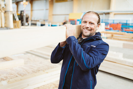 Confident happy worker in a carpentry or woodworking factory