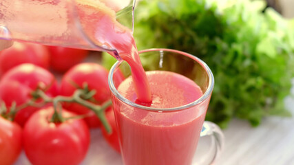 tomato juice with sprig of tomatoes on background. Tomato juice is poured into a glass.