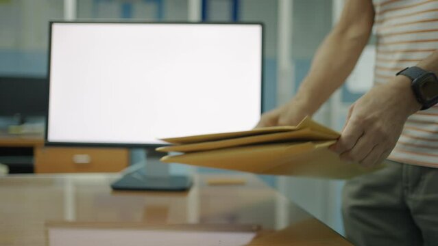 Man walks into the room and puts the brown envelope on the table.