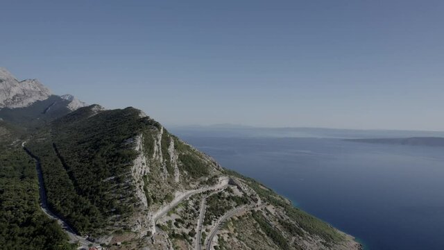 drone video over the mountain pass of the homeland war on the Makarska riverbank, frontal shot moving forward leaving the road behind and ending on the top of the mountain.