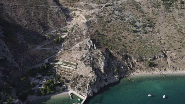 drone video over Zadvarje Beach on the coast of Crocia located on the Makarska Riviera, boats are seen. descriptive lateral plan from a bird's eye view.