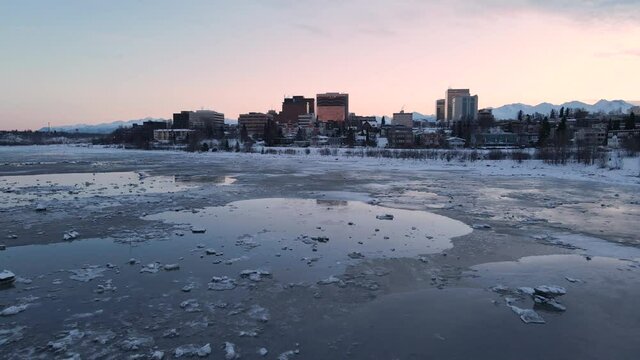 Flying over icy waters towards building in Anchorage alaska