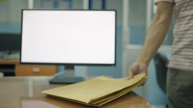 The man walked into the room and raised a brown envelope that was placed on the table.