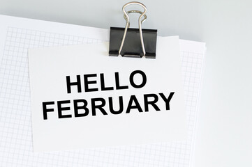 hello february text on a card that is attached to a notepad on a clip