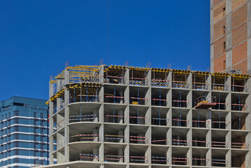 An abstract fragment of a modern construction of a high-rise residential complex. Construction of modern apartment buildings. Blue sky.
