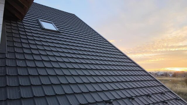 Closeup of house roof top covered with metallic shingles.Tiled covering of building