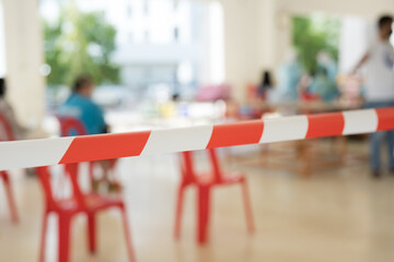 Row of empty red chairs and warning tape infection area.No entry sign concept.Selective focus.