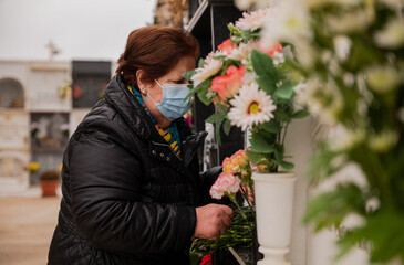 Old lady with mask mourning her family in cemetery. Almeria, Spain