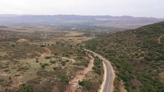 Panoramic aerial view of cars driving through Golan Heights hills and mountains in Northern Israel
