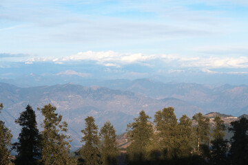 The peaks of the mountains of the Himalayas behind the trees. Natural background - mountain landscape.