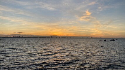 Beautiful sunset over the sea or ocean, bright and soft colors, magic light, small clouds in the sky