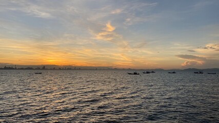 Beautiful sunset over the sea or ocean, bright and soft colors, magic light, small clouds in the sky