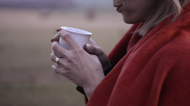 Woman drinking a cup of hot tea or coffee in cold weather