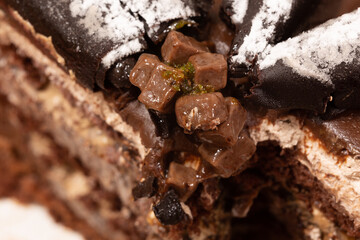 Cube chocolate pieces on sliced cake. There are bitter chocolate pieces in rolls on the cake. Cube...
