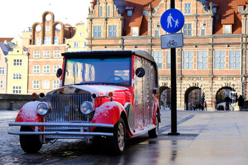Red retro car in the Old Town of Gdansk. In the background the Green Gate. Poland. 