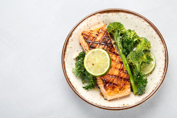 Baked salmon with vegetables on light background.