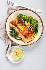 Baked salmon with vegetables on light background.