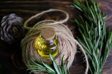 Rosemary oil. Rosemary essential oil jar glass bottle and branches of plant rosemary with flowers on rustic background. 