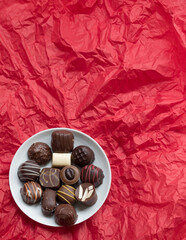 Assorted Chocolates on White Round Plate on Red Background