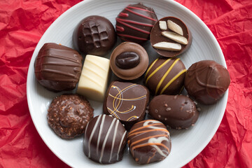 Assorted Chocolates on White Round Plate on Red Background