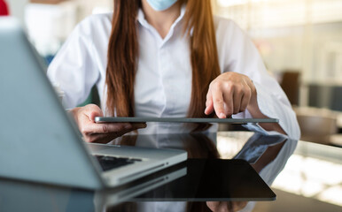 Woman hands is typing on a laptop and holding smartphone