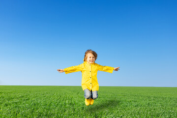 Happy child jumping in green spring field