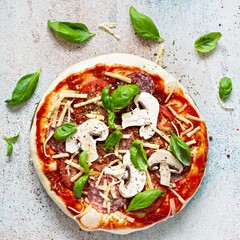 Cooking Italian pizza with tomato sauce, fresh tomatoes, cheese, mushrooms, salami slices and basil . Fresh food cooking concept at home. Semi-finished product, raw dough, step by step cooking.

