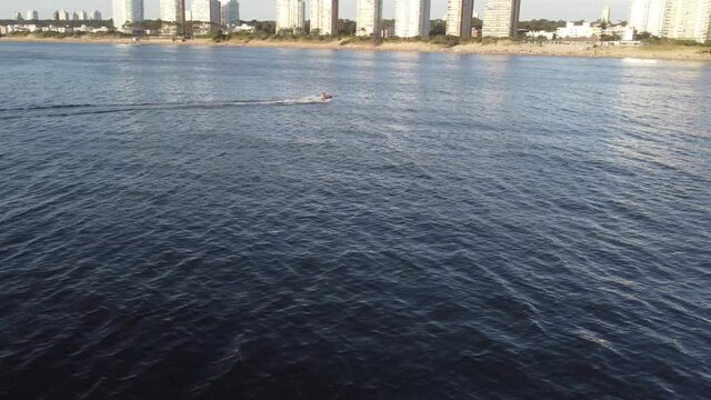 Aerial orbit shot of jet skl cruising over coastal bay of Punta del Este during sunny day in Uruguay